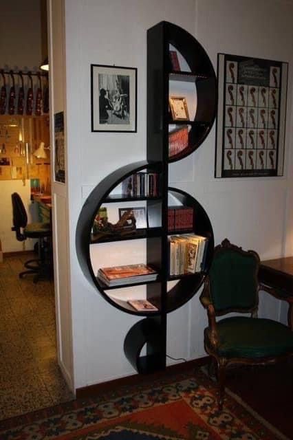 a book shelf in the corner of a room with pictures on the wall behind it