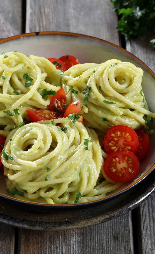 a bowl filled with pasta and tomatoes on top of a wooden table