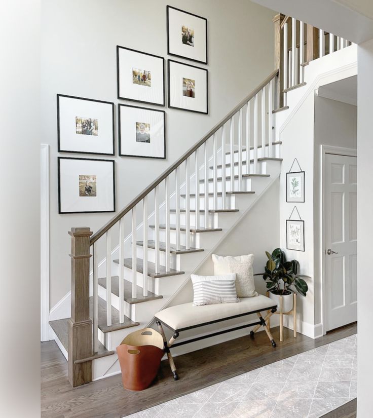 a living room filled with furniture and framed pictures on the wall next to a stair case