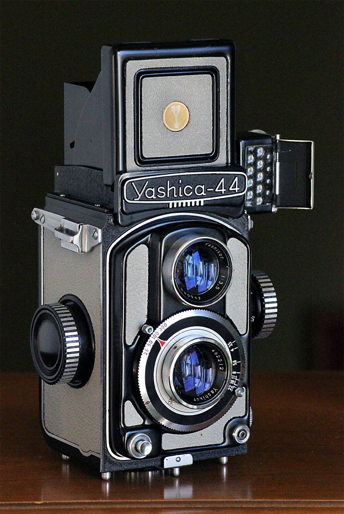 an old fashioned camera sitting on top of a wooden table