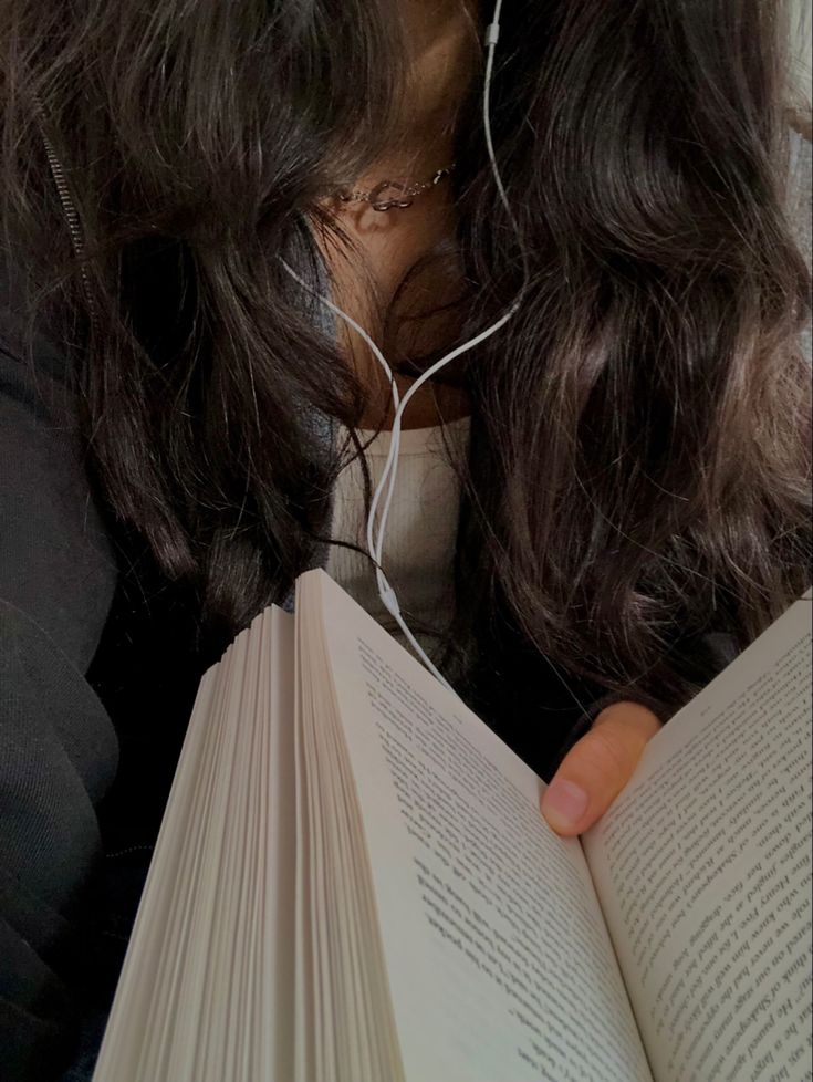 a woman reading a book with headphones on her ears