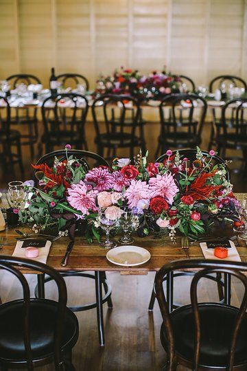 the table is set with flowers and place settings for guests to sit down at it