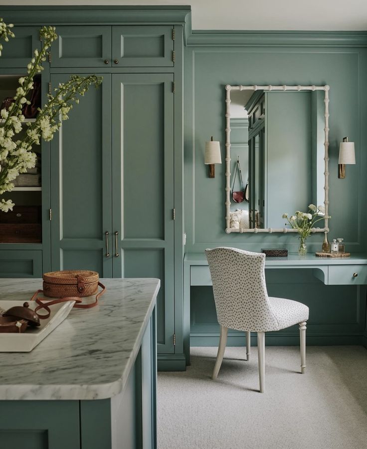 a room with green cabinets and a white chair in front of a mirror on the wall