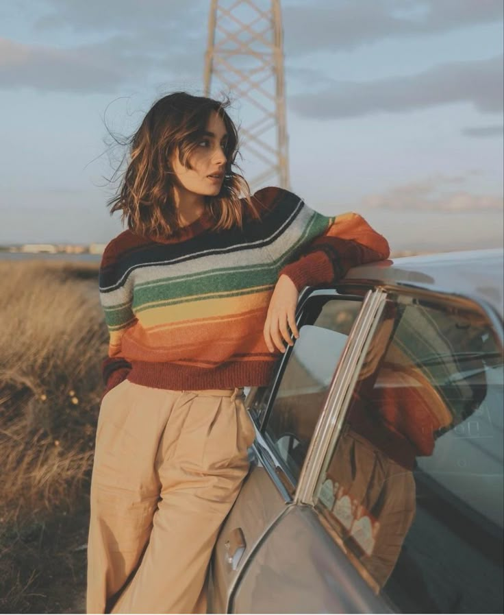 a woman leaning on the hood of a car