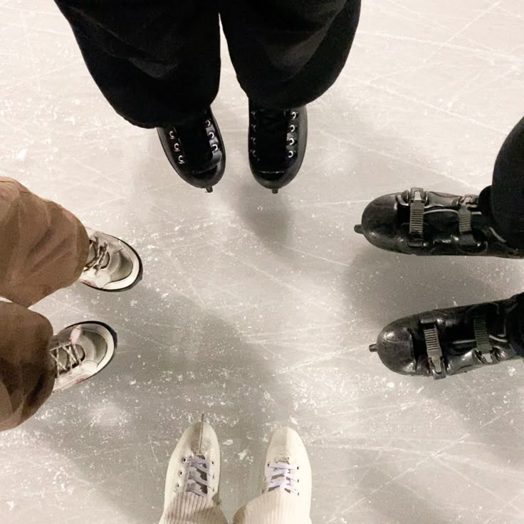 four people standing on an ice rink with their feet in the air and one person wearing white shoes