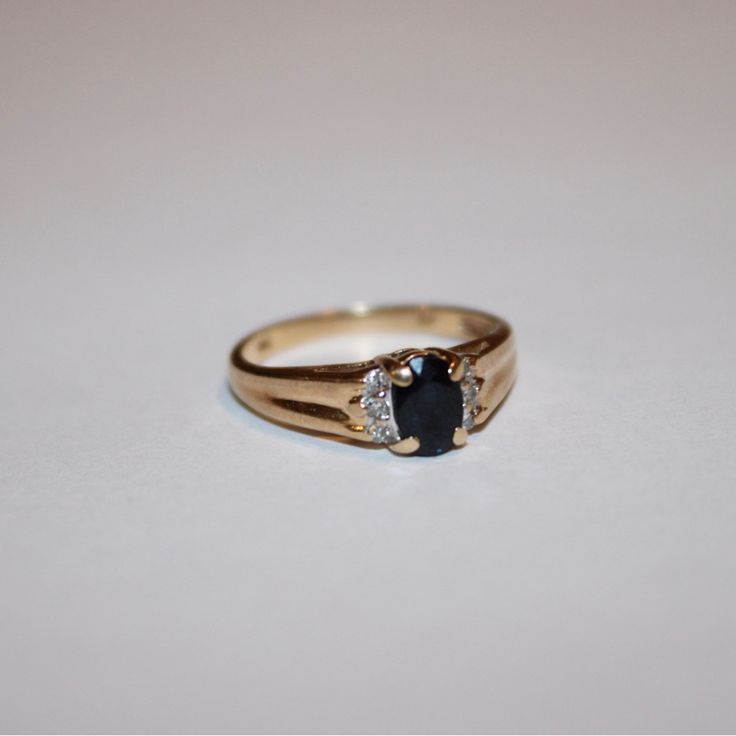 a close up of a ring on a white surface with a black diamond in the middle