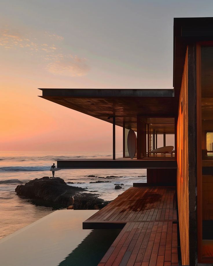 a person standing on the edge of a body of water next to a wooden building