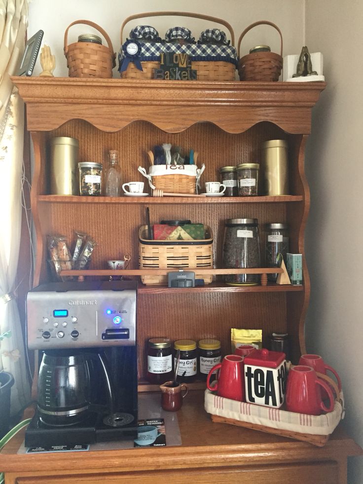 an old fashioned coffee maker on top of a wooden cabinet with baskets and other items