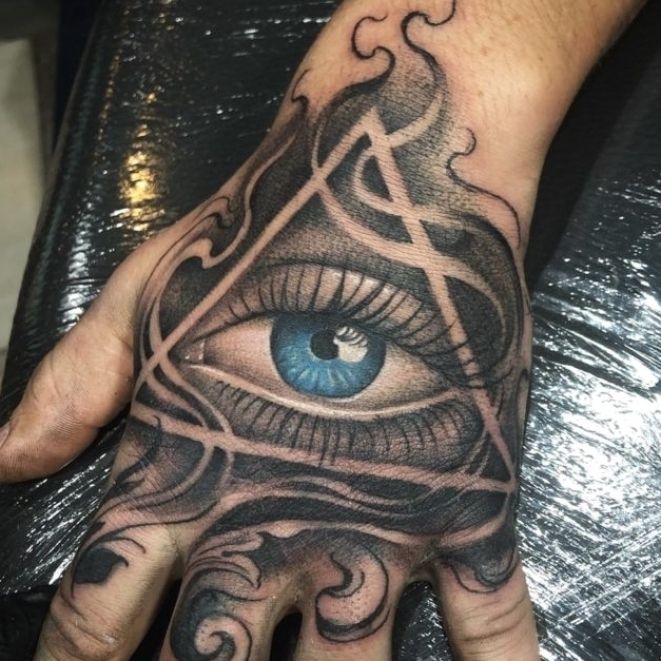 a hand with an all seeing eye tattoo on it