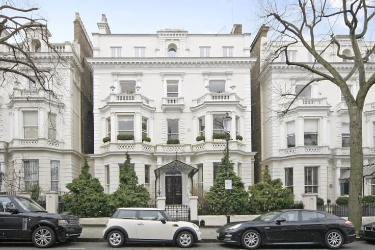 three cars parked in front of a large white building