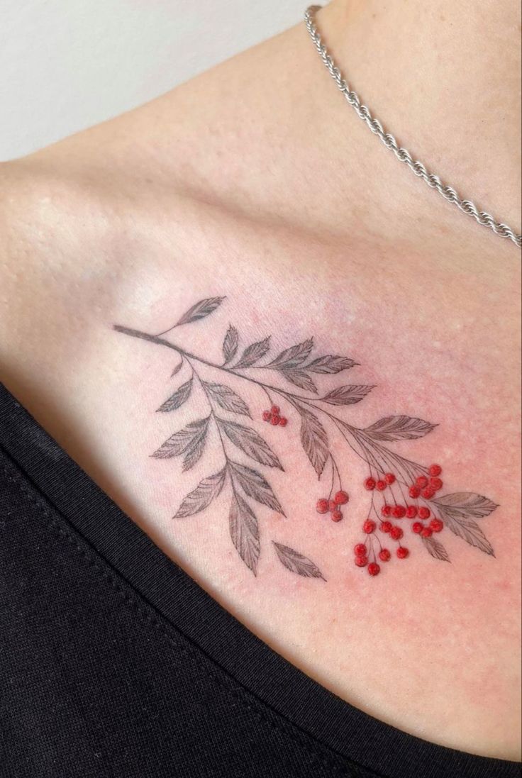 a woman's chest with red berries and leaves on it