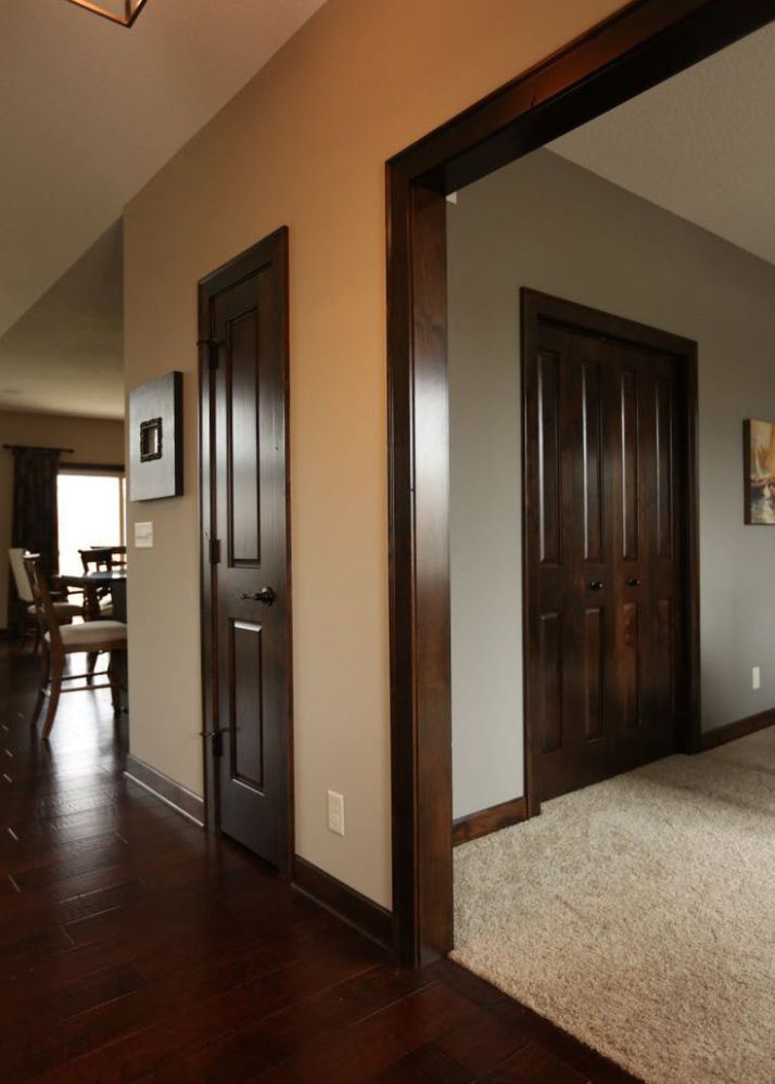 an empty living room with hardwood floors and two doors leading to the dining room area