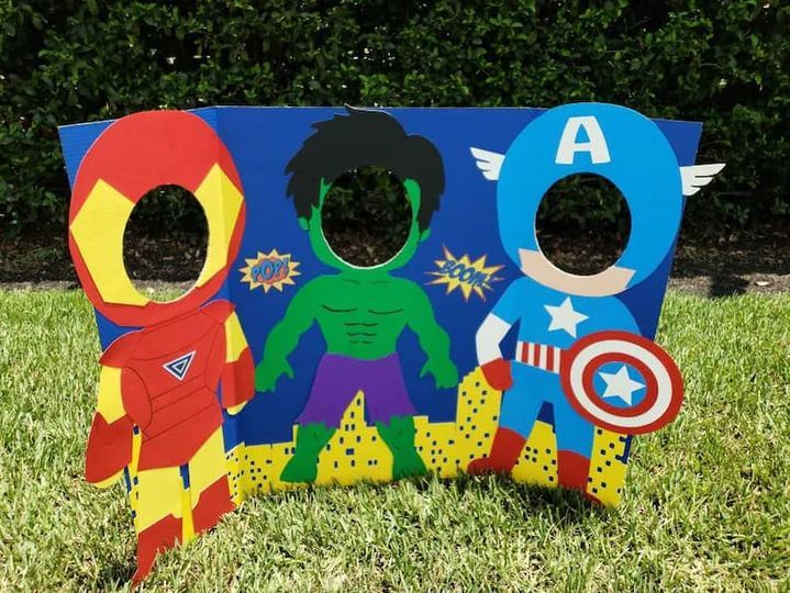 an outdoor play area with superheros and captain america cut outs on the grass in front of some bushes