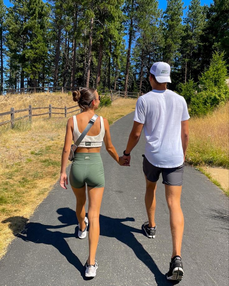 a man and woman walking down a road holding hands