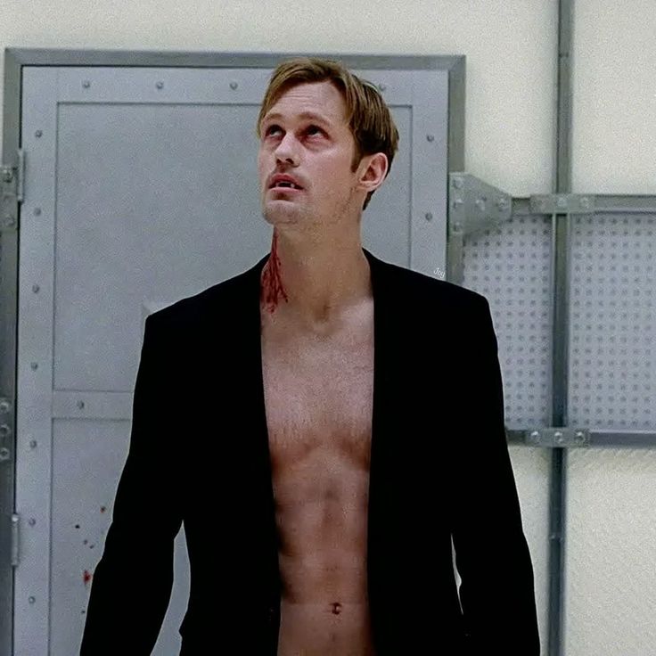 a shirtless man standing in front of a door with blood all over his body