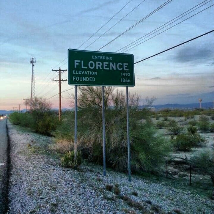 a street sign sitting on the side of a road near power lines and telephone poles