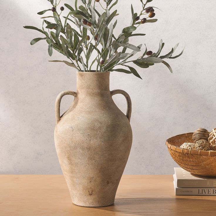 a vase with some flowers in it sitting on a table next to two books and a basket