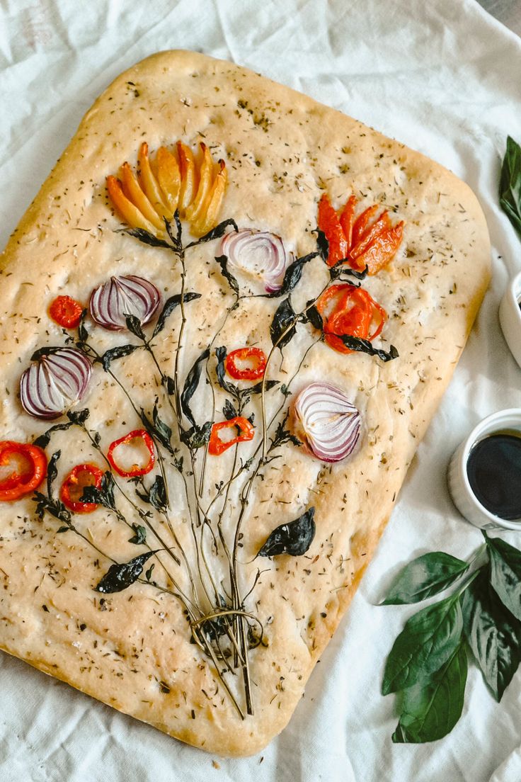 an artisan pizza with tomatoes and onions on it next to some dipping sauces