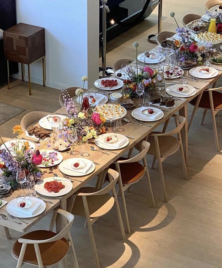 a long table is set with plates and flowers on it for an event or celebration