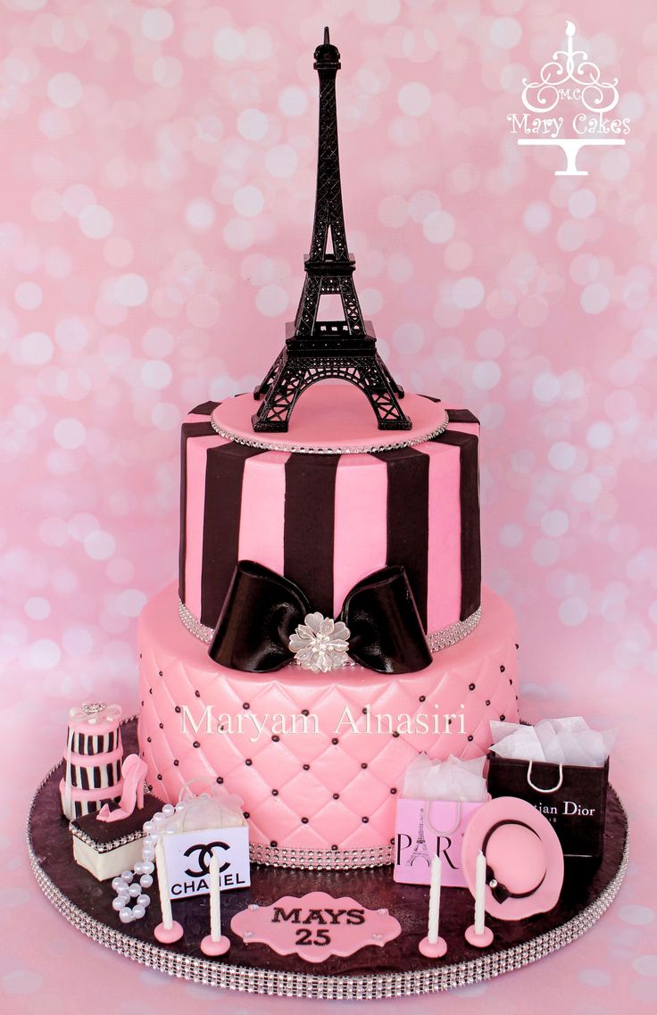 a pink and black paris themed cake with the eiffel tower in the background