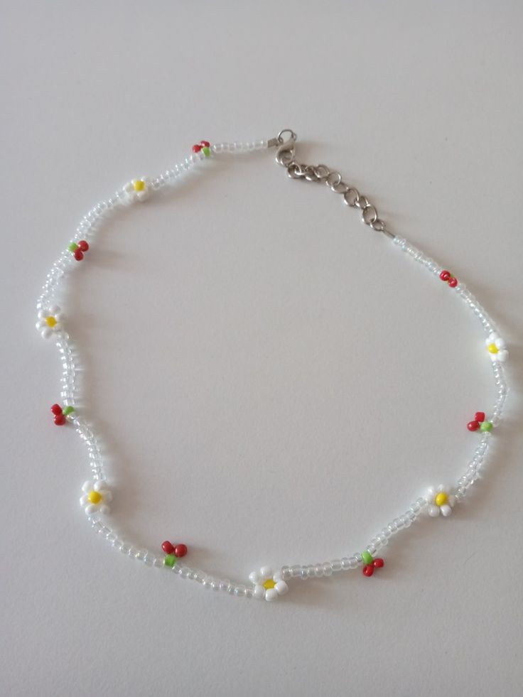 a white beaded bracelet with red, yellow and green beads on it's side