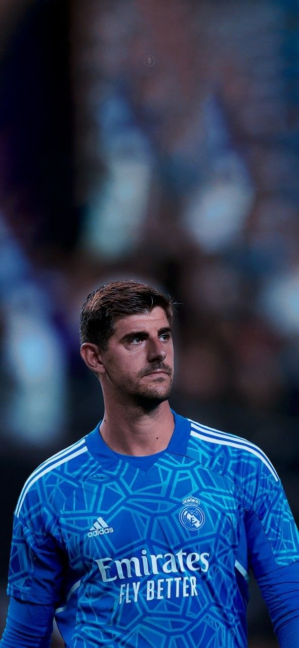 a soccer player is standing in the middle of a field with his head turned to the side