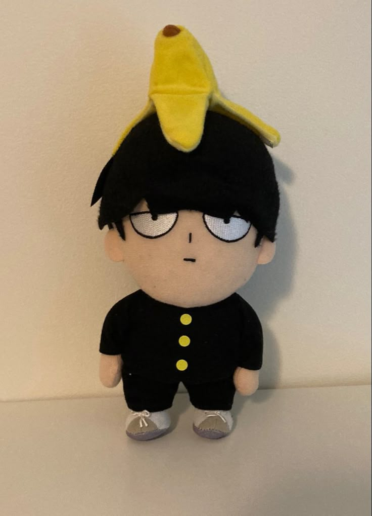 a small stuffed toy with a yellow hat on top of it's head and eyes