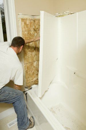 a man working on a shower wall in a bathroom that is being remodeled and remodeled