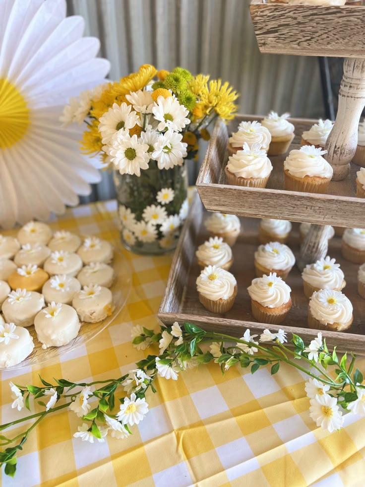 cupcakes and flowers on a table in front of a yellow checkered tablecloth