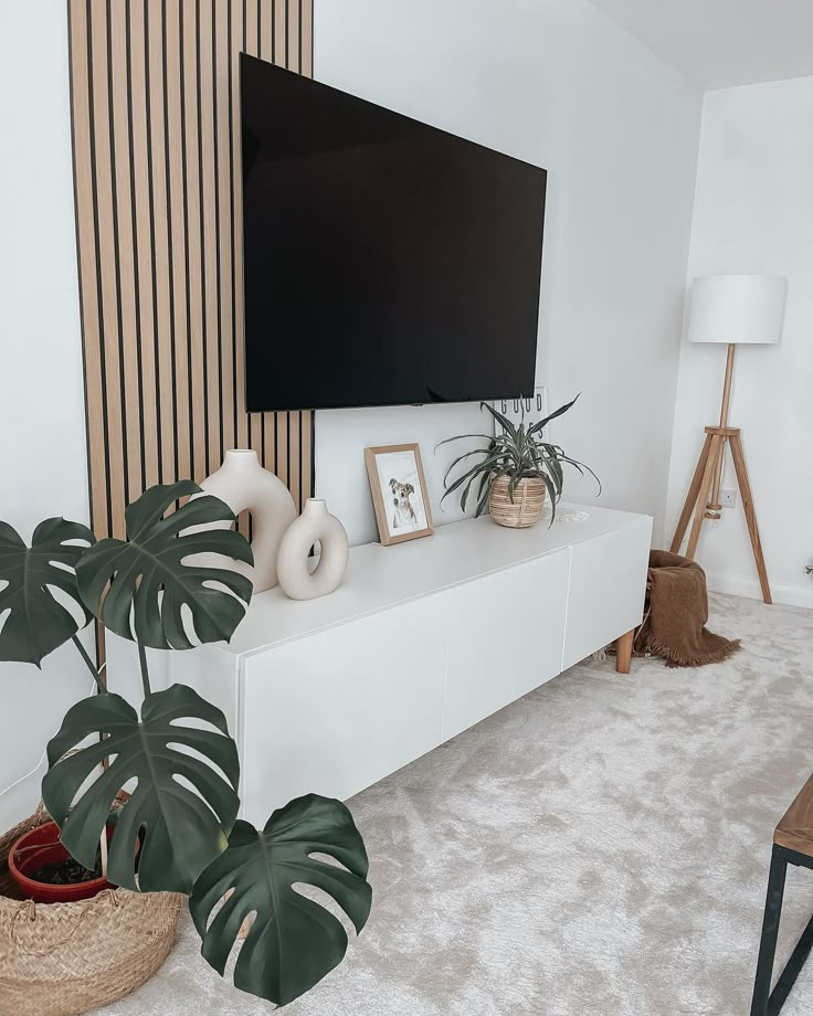 a flat screen tv sitting on top of a white shelf next to a potted plant