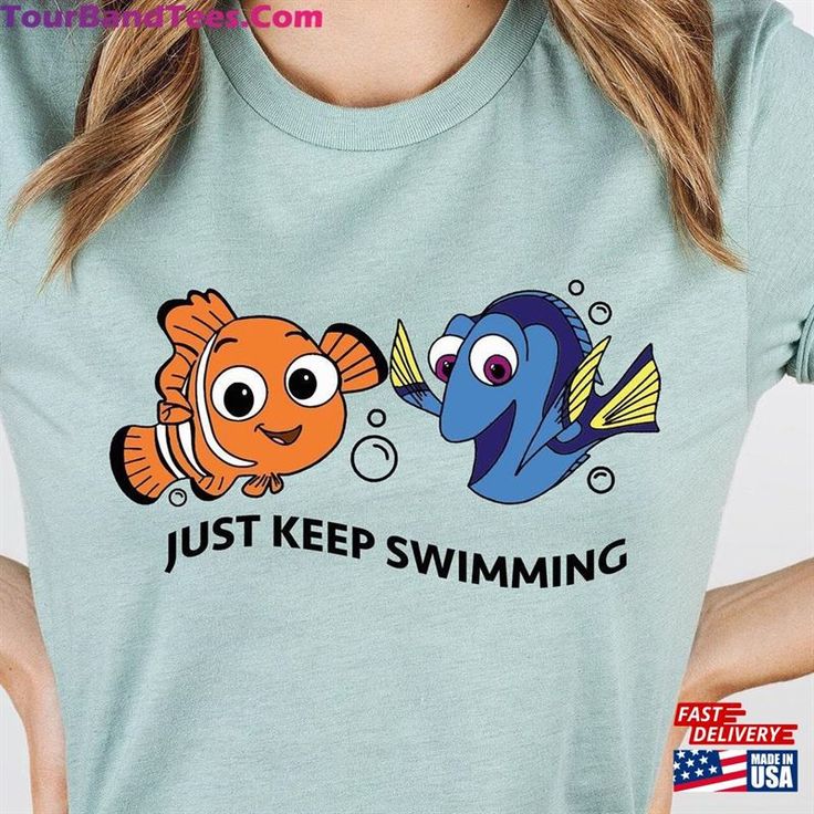 a woman wearing a t - shirt that says just keep swimming with an orange and blue fish