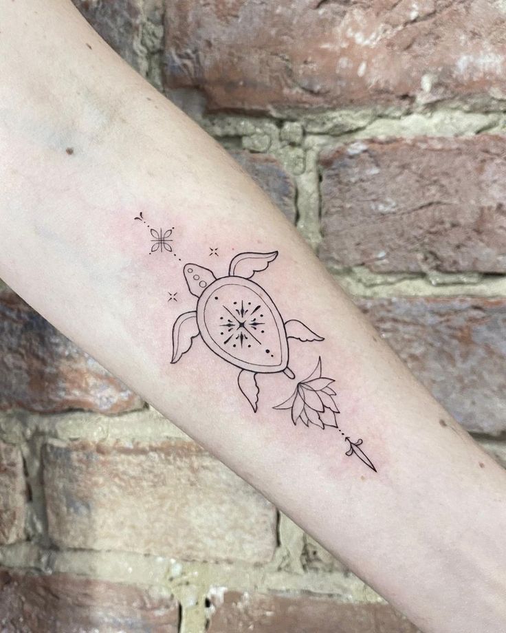 a small turtle tattoo on the left inner forearm and arm, with stars coming out of it