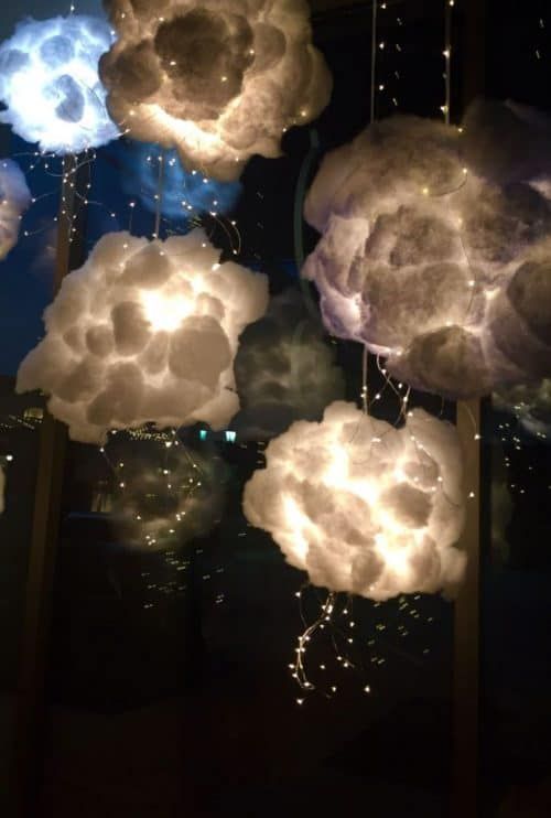 some clouds that are floating in the air with lights coming out of them and on top of each other