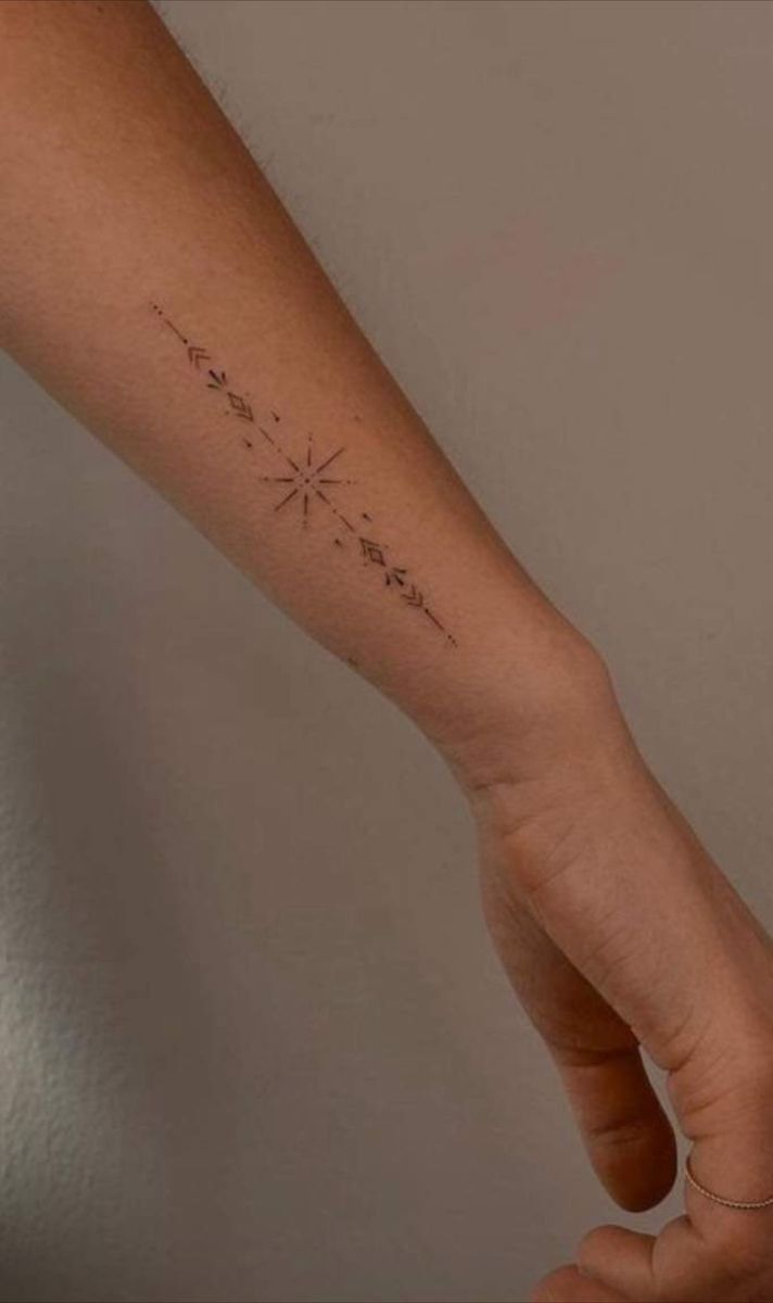 a person's arm with a small star tattoo on the left side of their arm