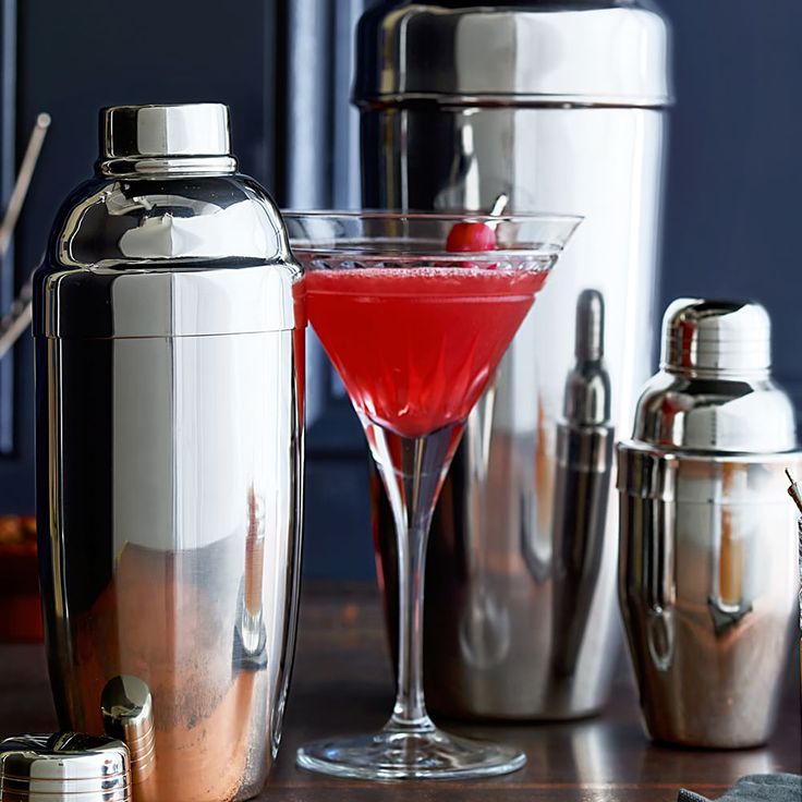 a table topped with cocktail glasses next to shakers