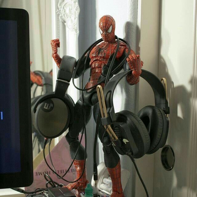 a spider - man with headphones is standing in front of a computer