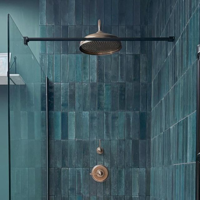 a bathroom with blue tiles and a shower head