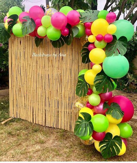 a bunch of balloons that are hanging from a bamboo structure with leaves and flowers on it