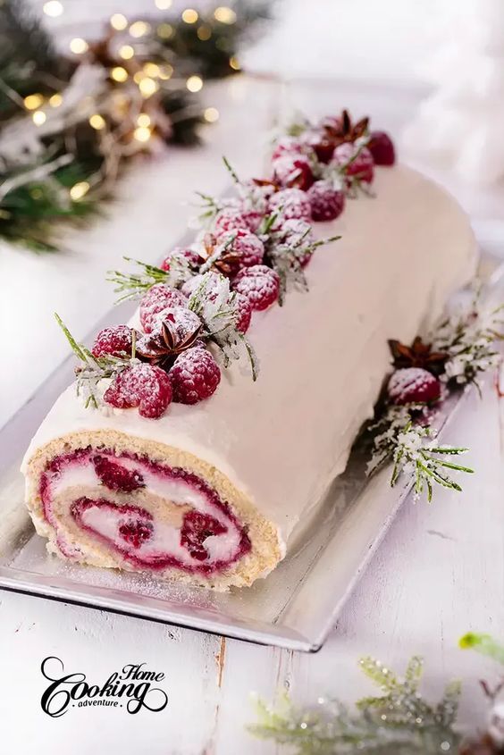 a white cake with raspberry filling on a platter next to christmas decorations