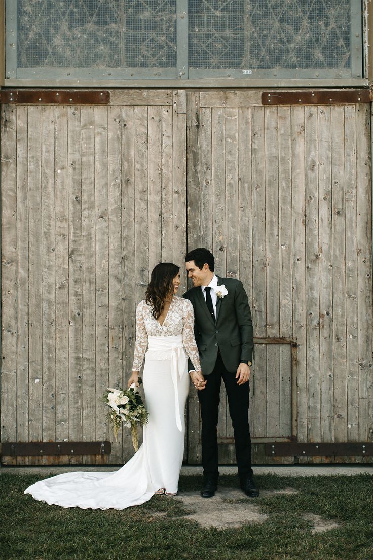 a bride and groom standing in front of a wooden fence