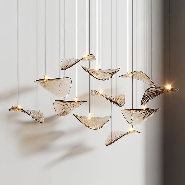 a group of lights hanging from strings in the shape of fish's tails on a white wall