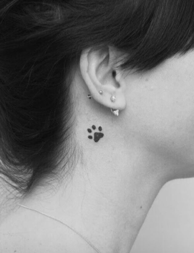 a black and white photo of a woman's ear with a dog paw tattoo on it