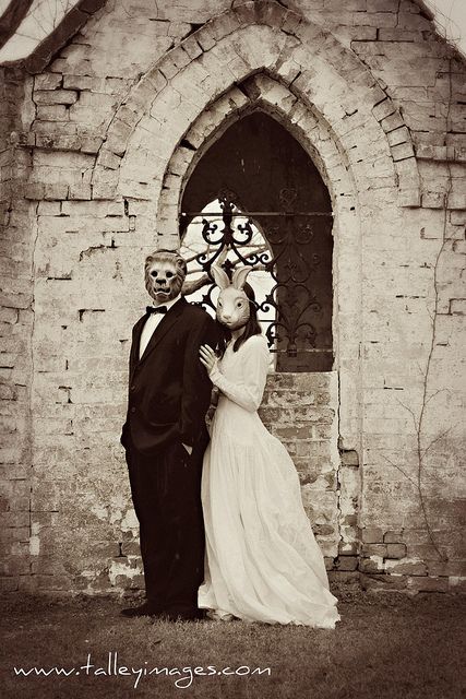 a bride and groom pose for a photo in front of an old brick church door