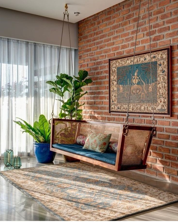 a living room filled with furniture and a large plant next to a wall hanging from the ceiling