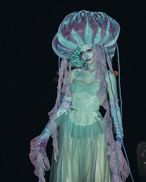 a woman dressed as a jellyfish walking down a runway