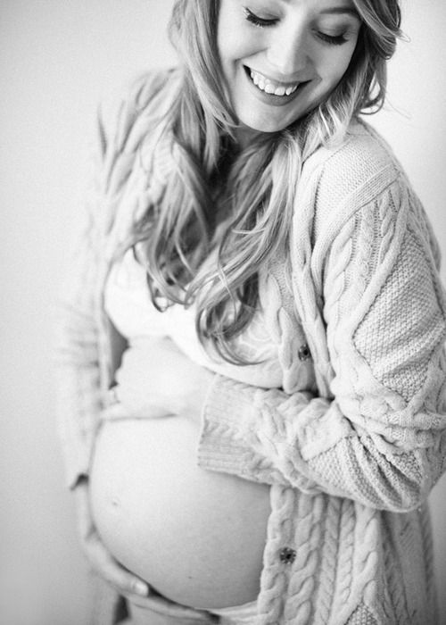 a pregnant woman smiles while holding her belly