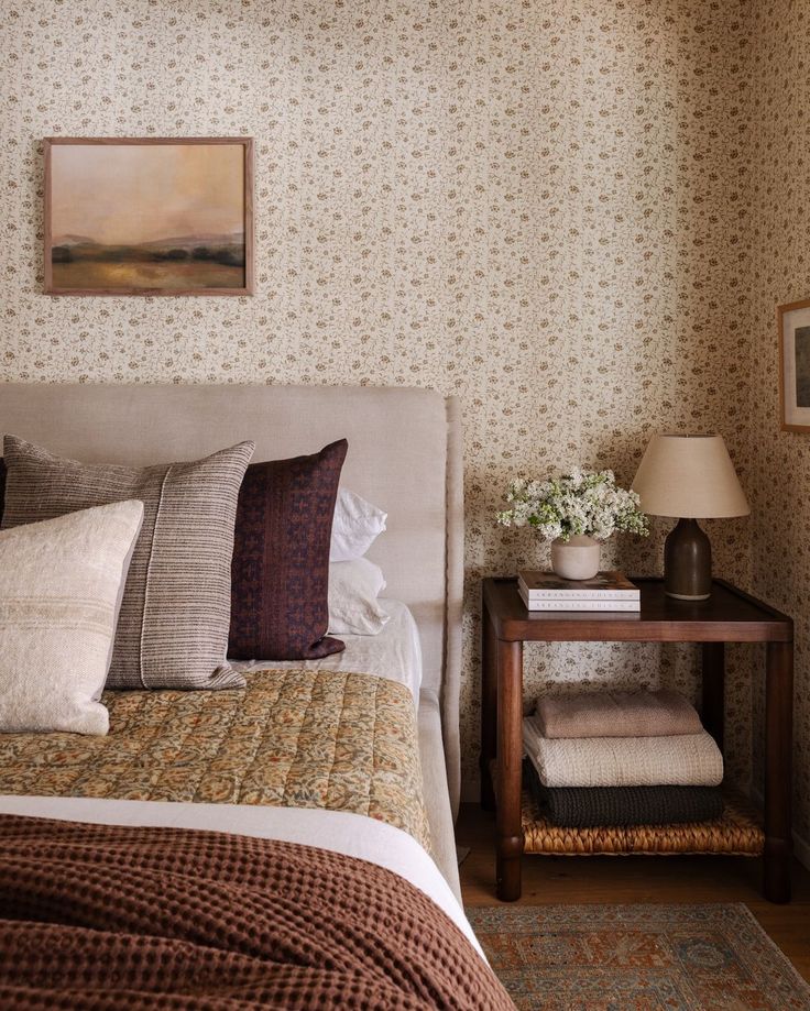 a bed sitting next to a night stand on top of a wooden table in a bedroom