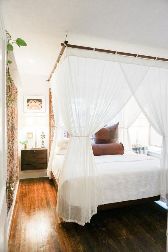 a bedroom with a white canopy bed and wooden floors