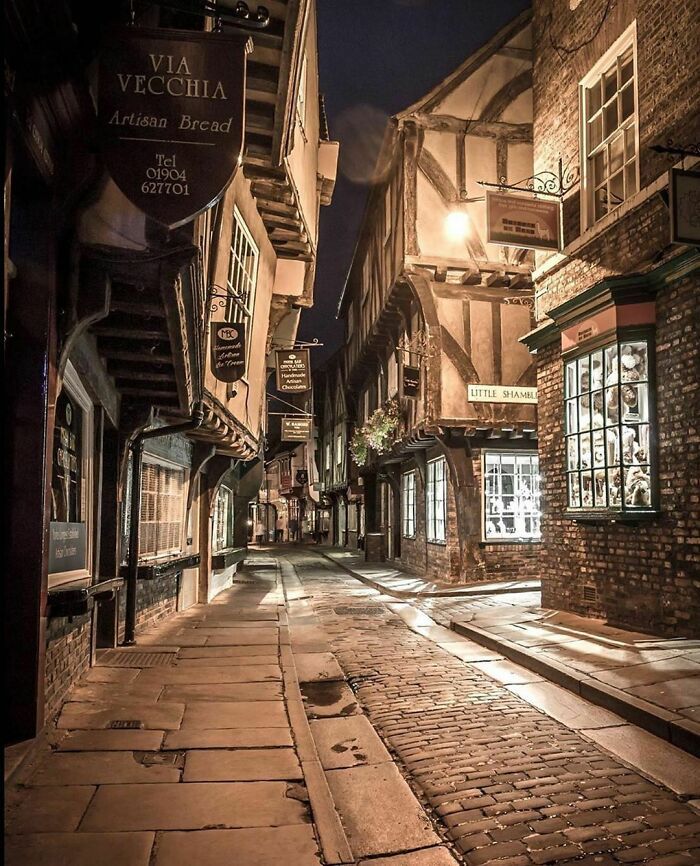 an empty street at night with cobblestones and old buildings on both sides, in the middle of town