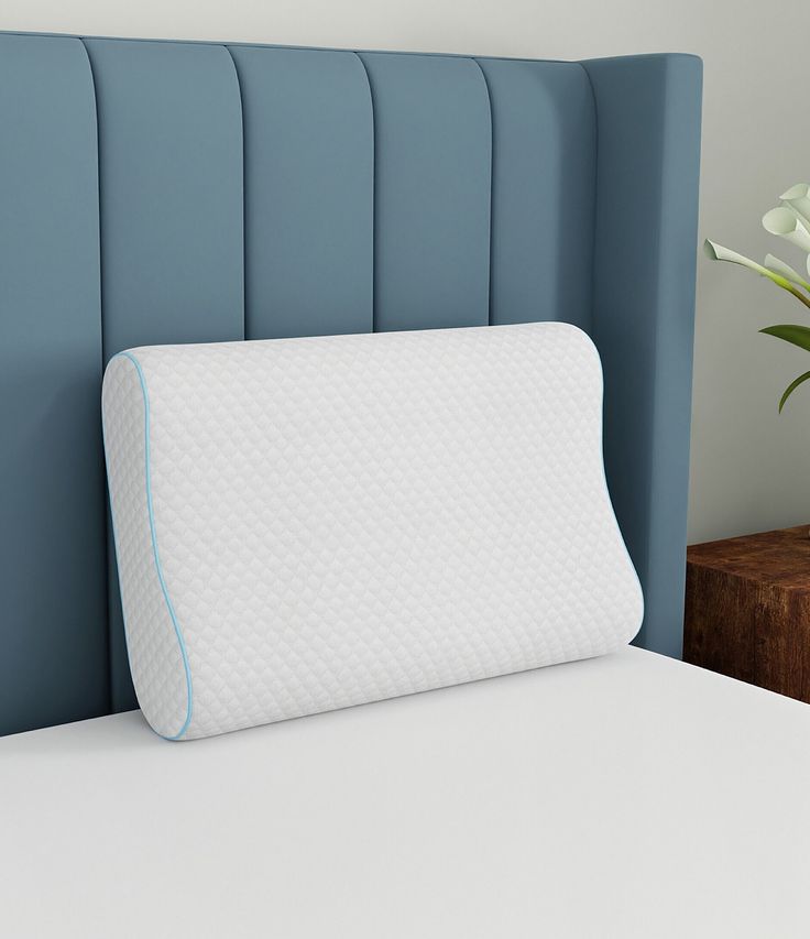 a white pillow sitting on top of a blue headboard